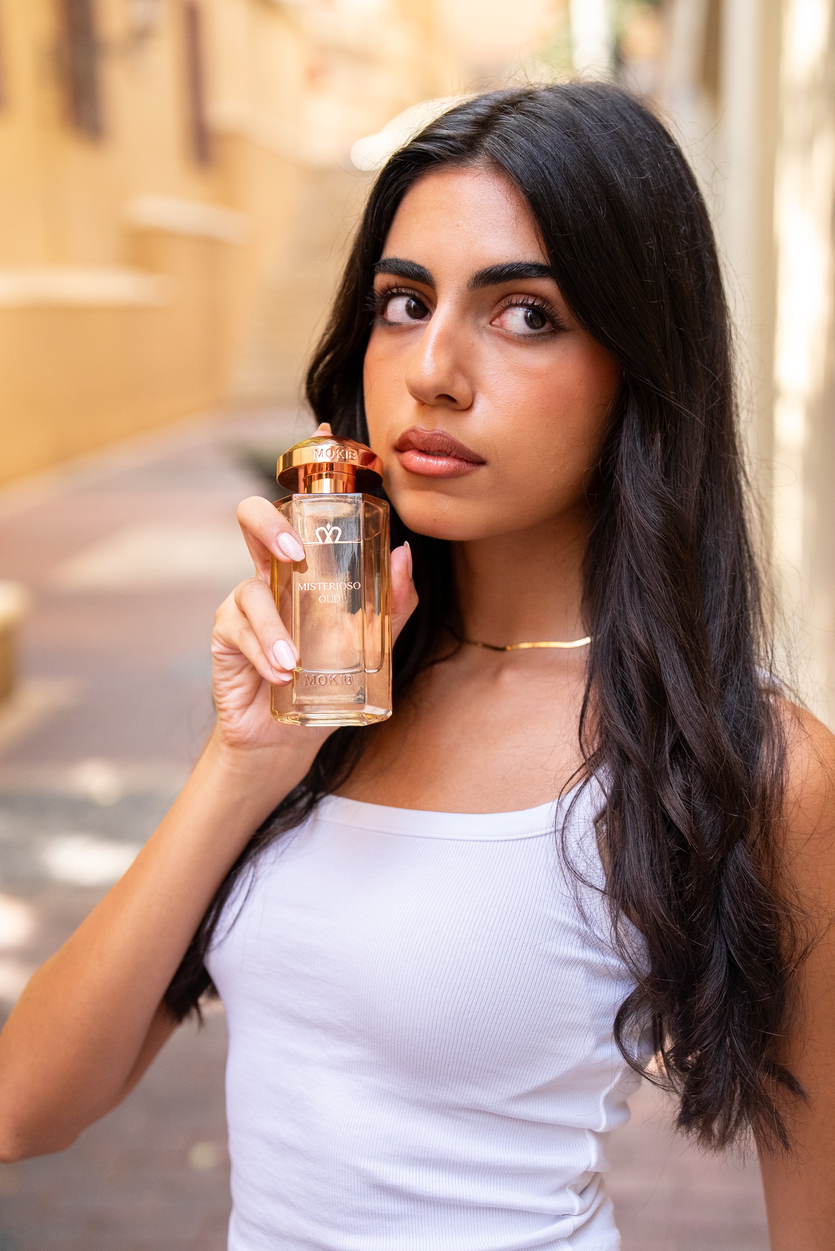 Woman holding a perfume bottle outdoors
